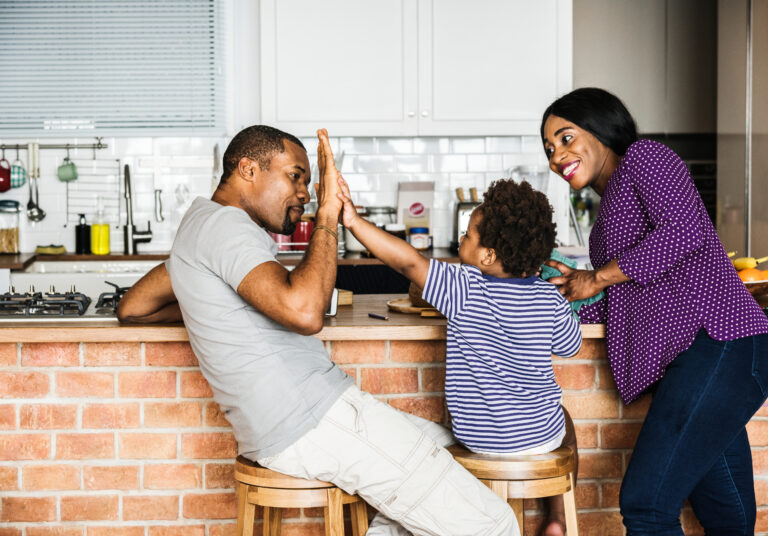 Father and son high-fiving in their kitchen after a rate and term refinance